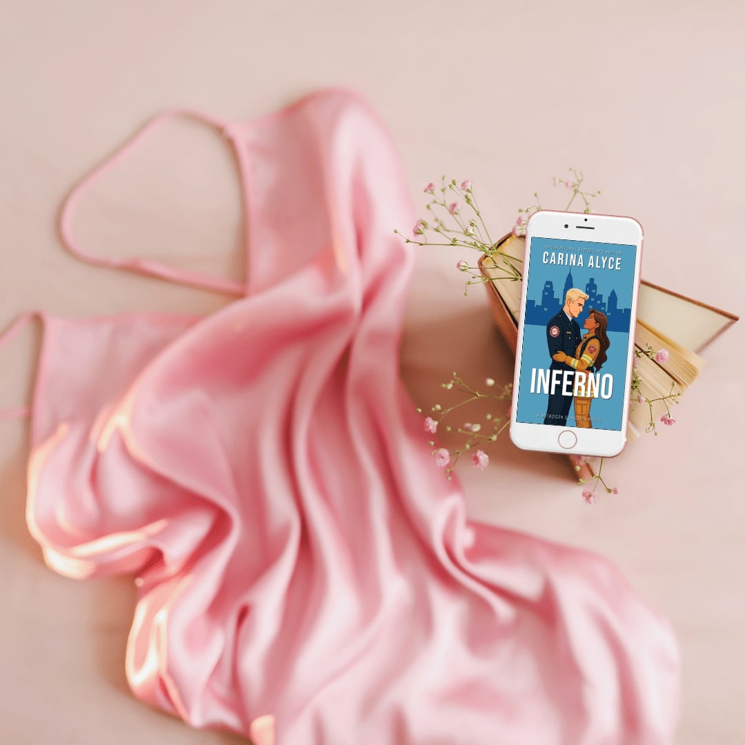 Phone displaying a book cover titled 'Inferno' by Carina Alyce on a pink fabric background