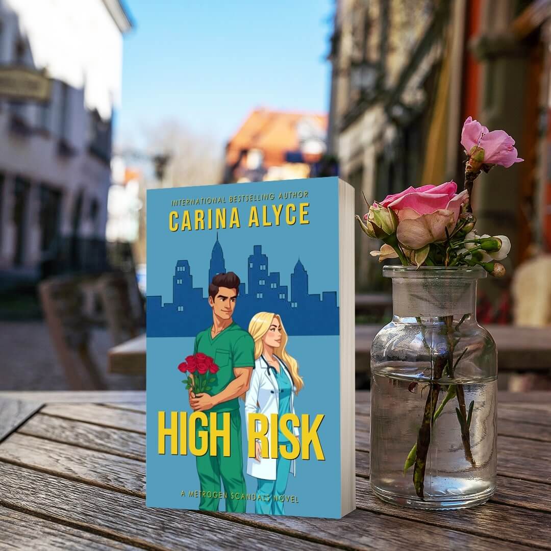 Book titled 'High Risk' by Carina Alyce on a wooden table with a vase of flowers.