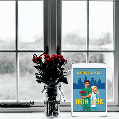 Tablet displaying a book cover with a bouquet of red roses in front of a snowy window.