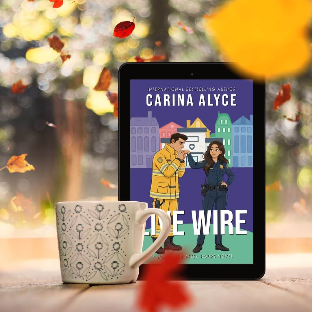 Tablet displaying a book cover with two characters and the title 'The Wire' by Carina Alyce, with a mug in the foreground and blurred autumn leaves in the background.