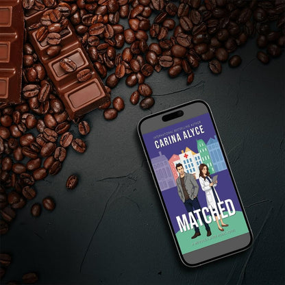 Phone displaying 'Matched' book cover with coffee beans and chocolate bars on a dark surface