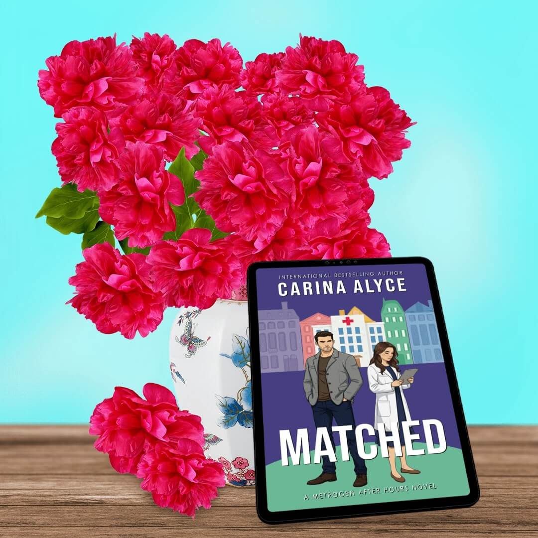 Book titled 'Matched' by Carina Alyce with pink flowers on a wooden surface and blue background
