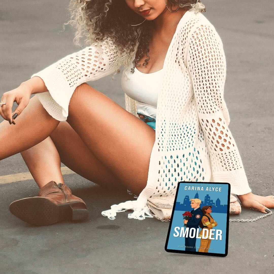 Woman in white outfit sitting on a road with 'Smolder' book cover displayed.