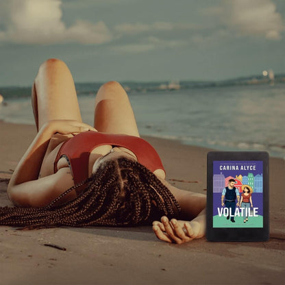 Person lying on a beach with a tablet displaying a book cover titled 'Volatile' by Carina Alyce.