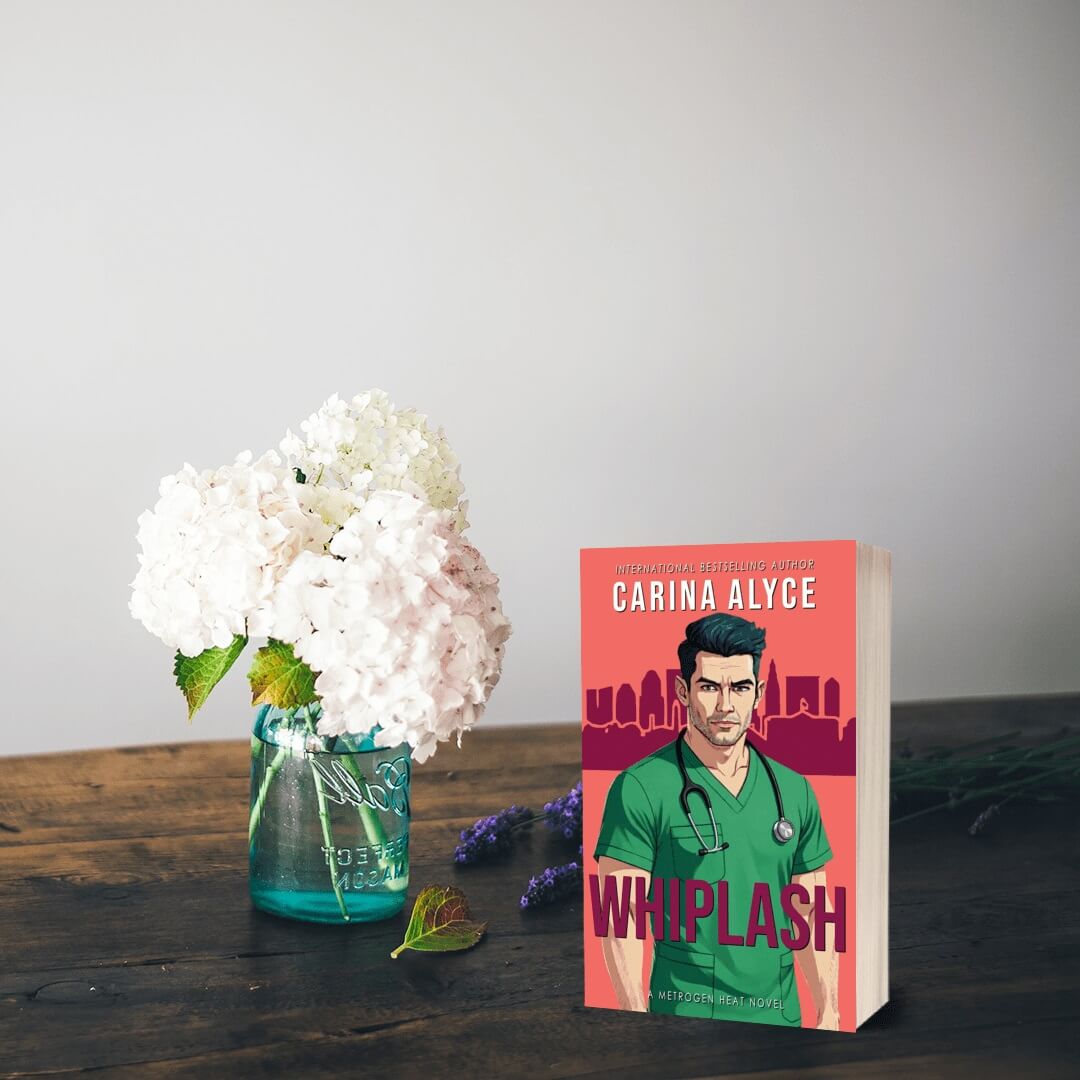 Book titled 'Whiplash' by Carina Alyce with a vase of flowers on a wooden surface.