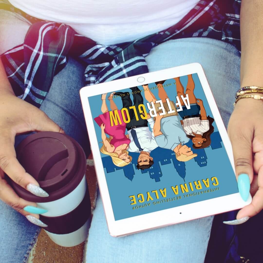 Person holding a tablet with a book cover displayed, wearing a plaid shirt and holding a coffee cup.