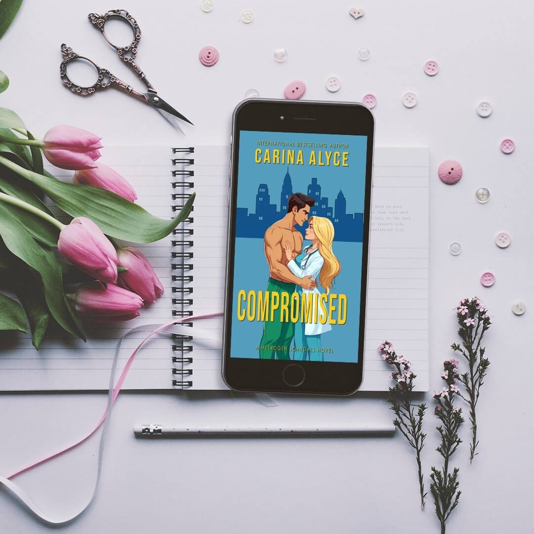 Phone displaying 'Compromised' by Carina Alyce with flowers and stationery on a white background