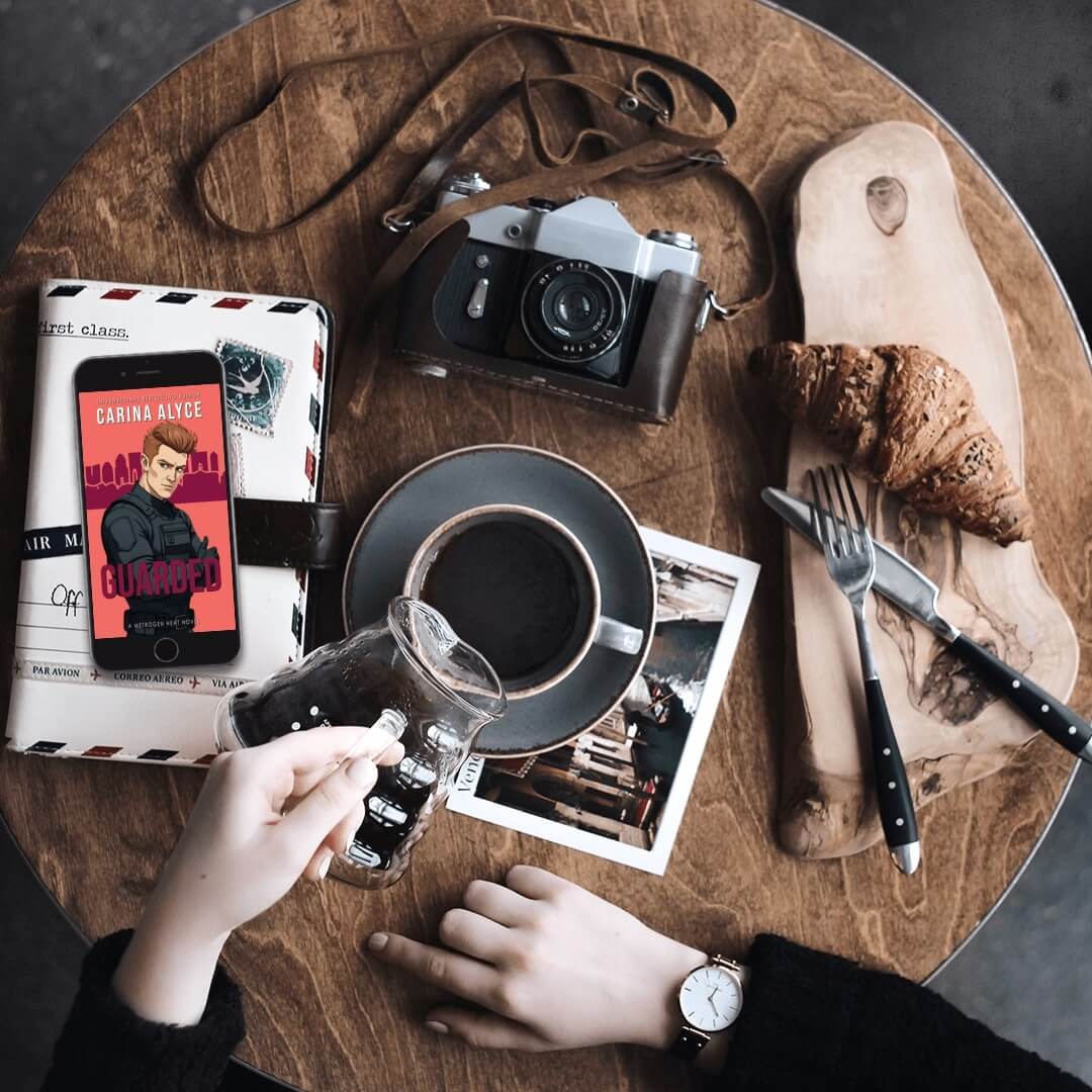Wooden table with coffee, croissant, camera, and other items