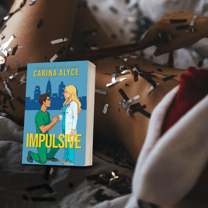 Book titled 'Impulsive' by Carina Alyce on a surface with decorative elements.