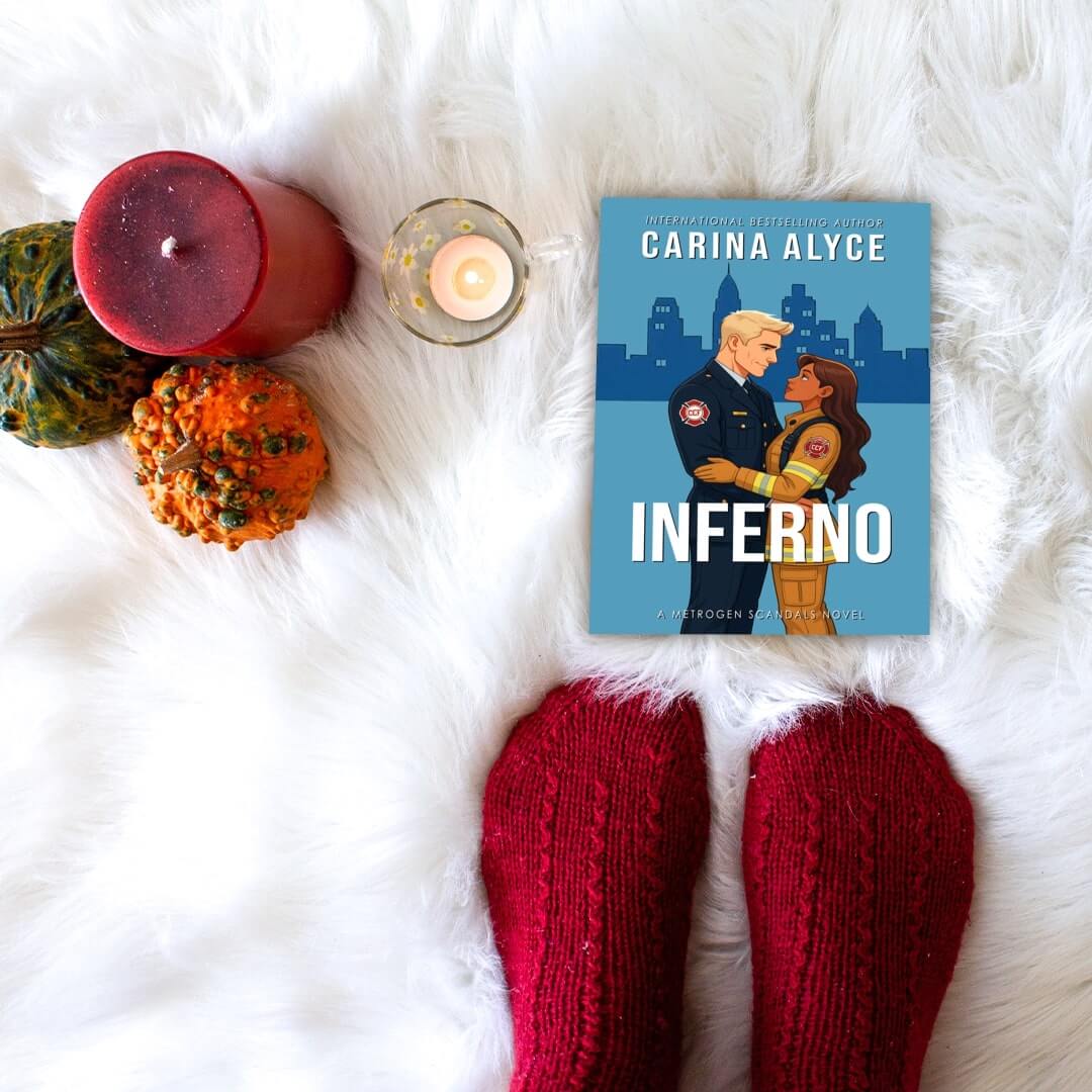 Book titled 'Inferno' by Carina Alyce on a white fur surface with candles and pumpkins.