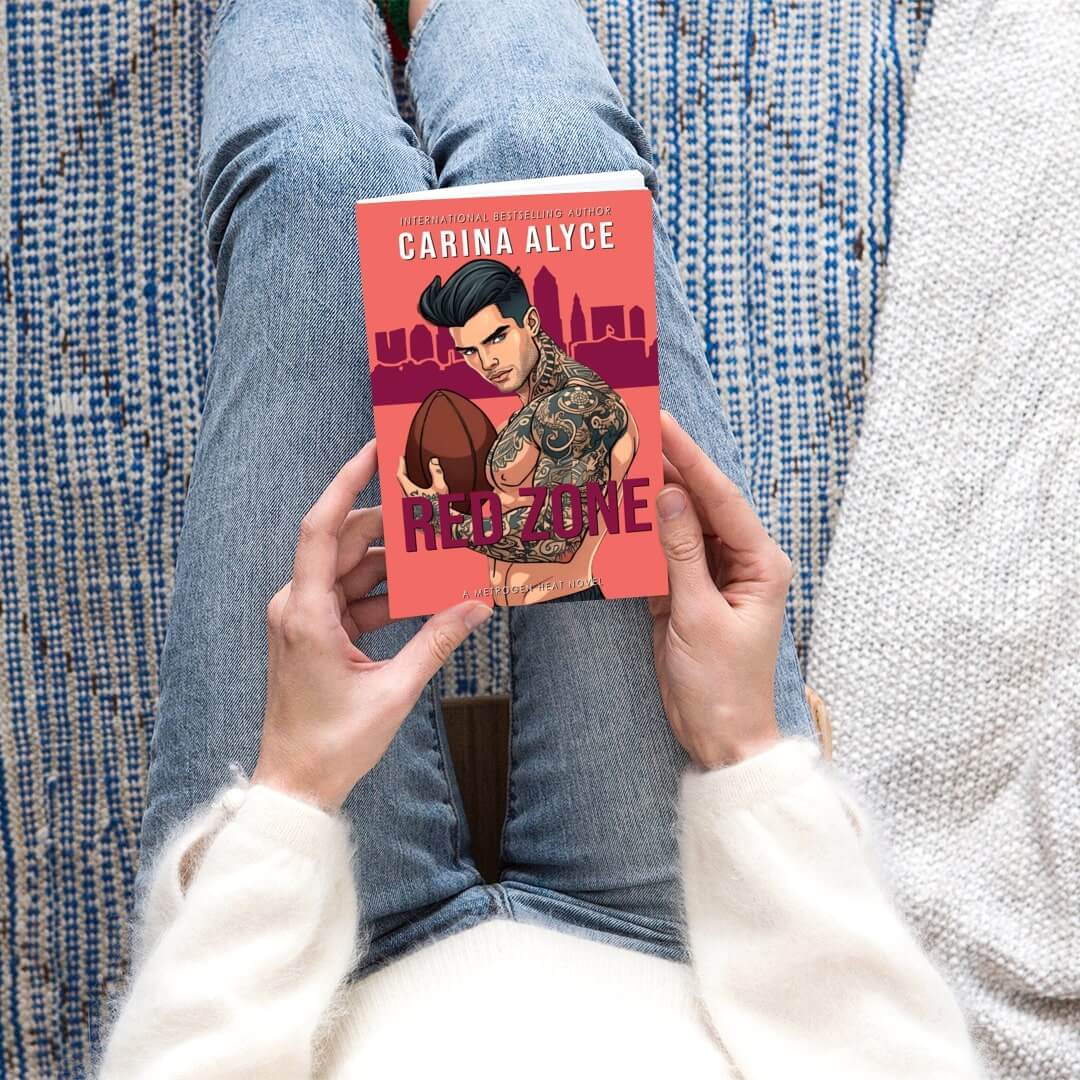 Person holding a book titled 'Red Zone' by Carina Alyce on a textured surface.