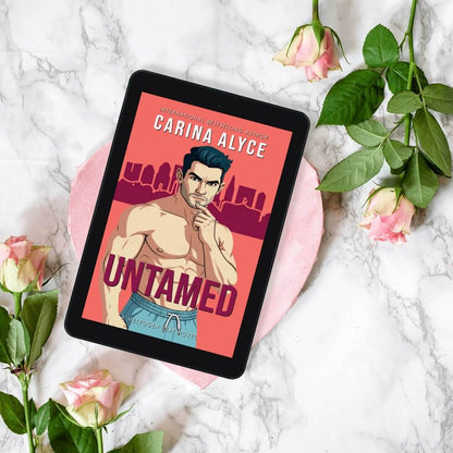 Tablet displaying the book cover of 'Untamed' by Garina Alyce on a marble surface with flowers.