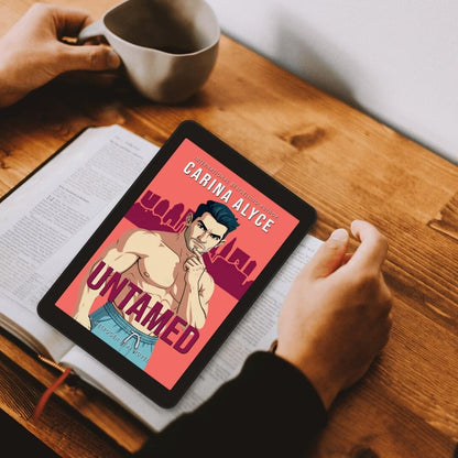Person holding a tablet with a book cover on a wooden table